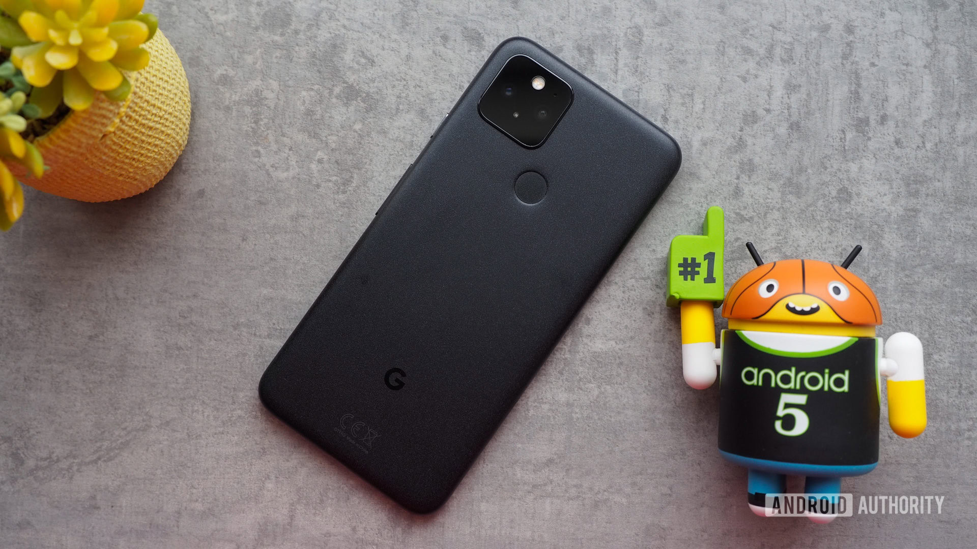 google pixel 5 back Google Pixel 5 seen from the back, laying on a table with a mini Android basketball figurine next to it