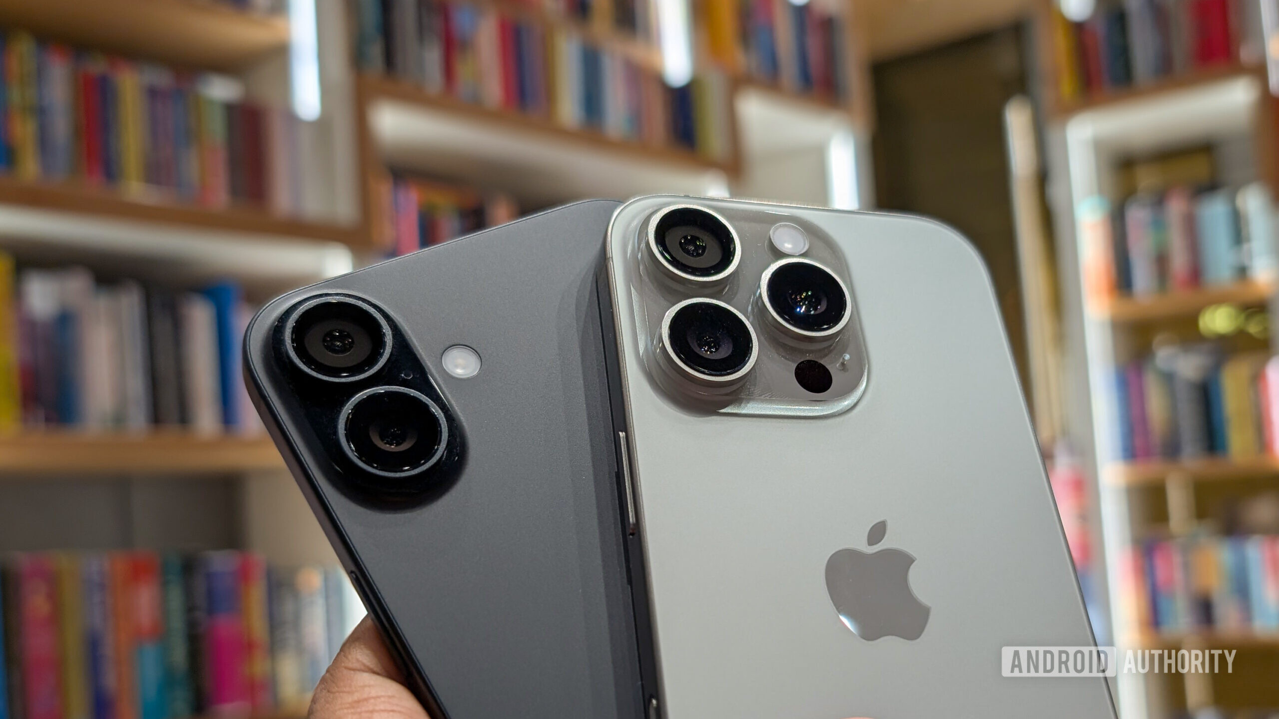 Apple iPhone 16 Plus in black color and iPhone 16 Pro in Natural Titanium color held out in hand, focusing on the camera Apple iPhone 16 Plus in black color and iPhone 16 Pro in Natural Titanium color held out in hand, focusing on the camera
